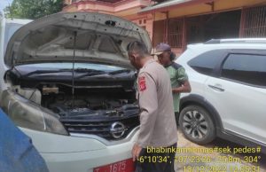 Anggota Polsek Pedes, membantu perbaiki mobil dinas desa yang rusak. (Lintasbatas.news)