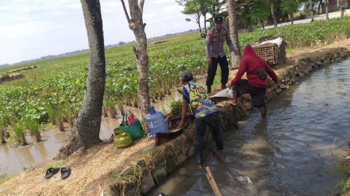 Bantu Petani, Anggota Polsek Pedes Gotong Royong Bersihkan Saluran Irigasi